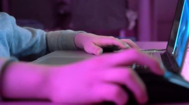 Çocuk fareye tıklayarak klavyeye basıyor. Çocuk video oyunu oynuyor ve bilgisayar kullanıyor. Geleceğin rgb arka ışıkları