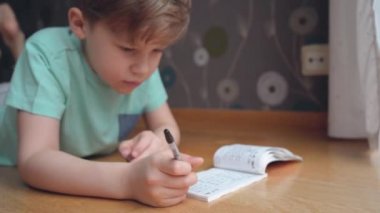 Çocuk konsantre oluyor ve düşünüyor. Çocuk ödevlerini yapıyor ve defterine yazı yazıyor. Matematik yapıyorum..