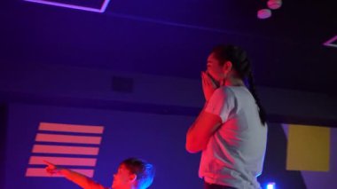 Futuristic concept: Mother and son amazed by augmented reality technology and vr video games. Happy faimly enjoying virtual reality game room.