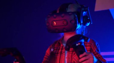 Futuristic concept: Close up girl using augmented reality equipment. Adult enjoying virtual reality video head set. Playing video games in vr. Futuristic RGB lights