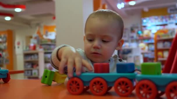かわいい焦点を当てた赤ちゃんの男の子は店で幼児のおもちゃで遊ぶことを学ぶ クローズアップポートレートショット — ストック動画