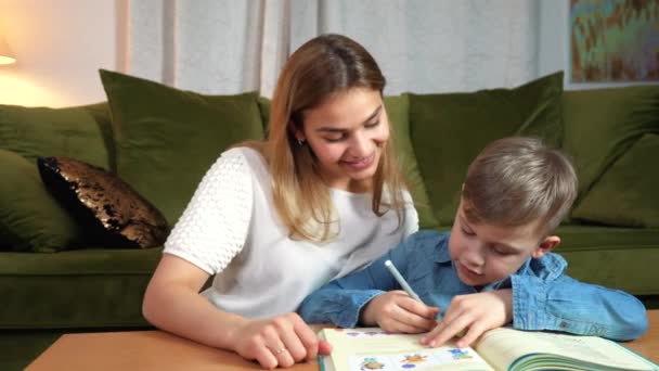 自宅で一緒に勉強する魅力的な母親と息子 家庭教育の概念 ナニーは家で宿題をしている少年に教える — ストック動画