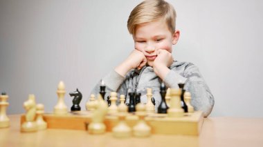 Satranç oynayan konsantre çocuk. Kafkasyalı çocuk satranç oynarken düşünür. Beyaz arkaplan