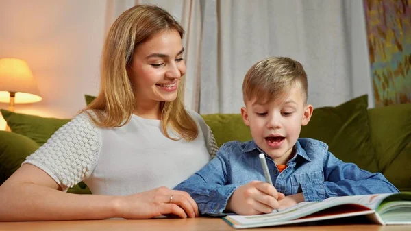 美しい母親と息子は家で一緒に勉強します 家庭教育の概念 ナニーは家で宿題をしている少年に教える — ストック写真