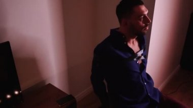Telefonuna uzanan sandalyeye bağlanmış bir adam. Çıkmak için mücadele ediyor..