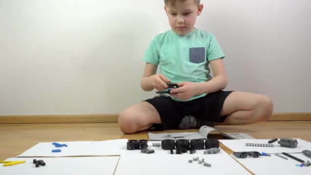 少年は建物のブロックで遊んでいる 小さなブロックで構築された小さなエンジニアの天才 おもちゃの車の部品のマクロショット — ストック動画