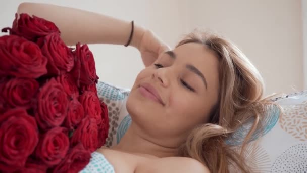 バラの花束をベッドに美しい若い女性 笑顔と夢 午前中は晴れと明るい日 ロマン主義 — ストック動画