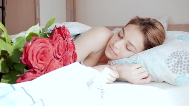 美しい若い女性が目を覚ますとバラの花束を受け取った ベッドの中で魅力的な女の子プレゼントを受け取ることを嬉しく思います ロマン主義 — ストック動画