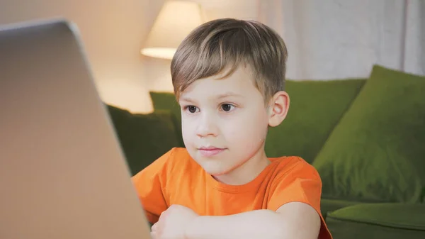 Cute boy studying home behind his computer. Child is enjoying his homework. Home education concept.