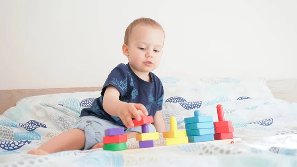 Cute small toddler doing brain exercises. Baby boy playing development montessori games.