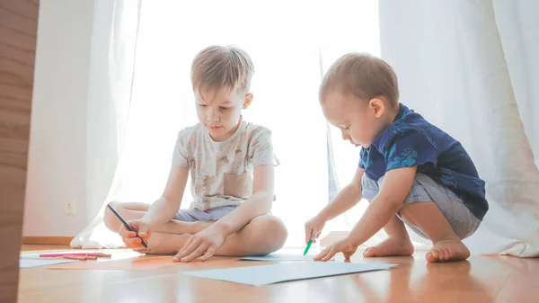 Oynayan ve öğrenen iki mutlu çocuk. Küçük kardeşler birlikte eğleniyor. Aile kavramı. 
