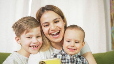 Oğullarıyla görüntülü görüşme yapan güzel bir anne. Mutlu bir aile evde selfie çeker ve görüntülü sohbet eder. Anneler Günü, birlik, bağlantı konsepti. 