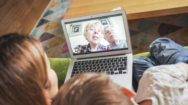 Dede ve ninesiyle görüntülü görüşme yapan genç bir anne. Aile, anne babasıyla webcam 'de iletişim kuruyor. Her yaştan insanı birbirine bağlayan modern teknoloji..