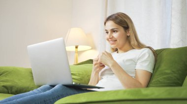 Kanepede gülümseyen genç bir kız görüntülü görüşme yapıyor. Kanepede oturan güzel bir kadın laptopuyla evden çalışıyor. Ailesi ve büyükleriyle görüntülü konuşma.. 