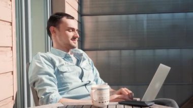 Başarılı bir iş adamı gülümseyerek hayattan zevk alıyor. Evde güneşli bir günde evde çalışan bağımsız bir menajer..