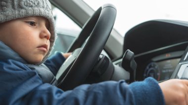 Gerçekten tatlı bir çocuk araba sürmeyi öğreniyor. Komik kavramsal portre fotoğrafı. 