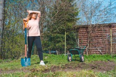 Arka bahçede çalışan, gülümseyen, genç, güzel bir kadın bahçıvan. Güzel bir kızın portresi peyzaj yapmak ve güneşli bir günde bahçesiyle ilgilenmek. 