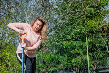 Arka bahçede çalışan, gülümseyen, genç, güzel bir kadın bahçıvan. Güzel bir kızın portresi peyzaj yapmak ve güneşli bir günde bahçesiyle ilgilenmek. 