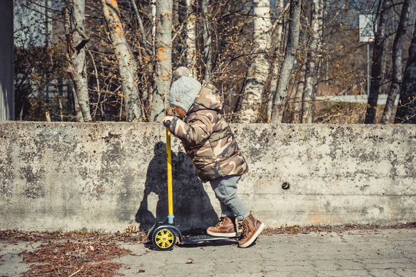 Güneşli bir günde scooter süren sevimli mutlu çocuk..