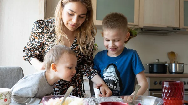 Güzel anne ve iki oğlu mutfakta yemek yapıyor. Mutlu aile kavramı.