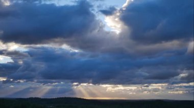 Akşam gökyüzünde süzülen koyu mavi bulutların arasından süzülen güneşin destansı ve pitoresk bir zaman atlaması. Güneş parlıyor ve bulutlarla kaplanıyor. Yaz ormanının havadan ve panoramik manzarası