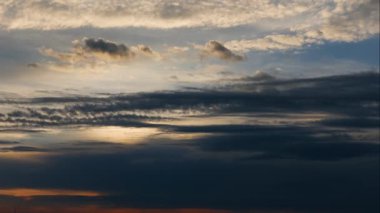 Alacakaranlık gökyüzünde hareket eden koyu mavi bulutların havadaki panoramik zaman geçişi. 4K 'da tepenin üstünden bak.