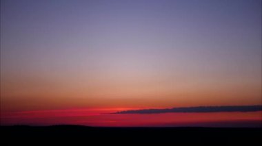 Pembe ve menekşe alacakaranlık gökyüzünün havadaki panoramik zaman akışı 4k 'de ufuk çizgisinde hareket eden uzun bulutlu hali.