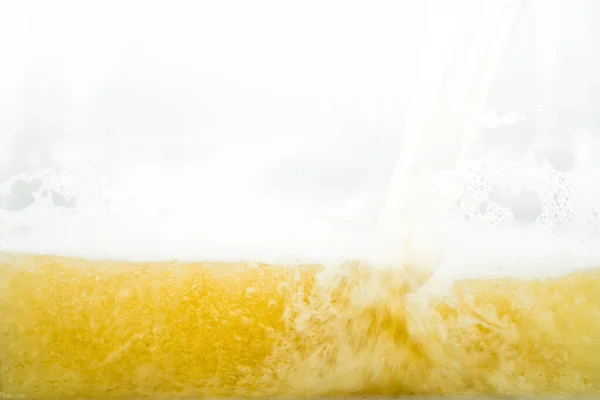 Close up of cool lager beer splash isolated on white background with realistic bubbles & froth in glass. Pouring golden craft beer on front view wave curve shape texture foam for pub & bar menu design