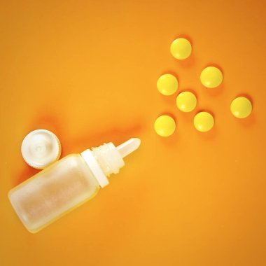 White plastic nasal spray with tablets on orange background - sinusitis, geniantritis, rhinitis and other diseases of ENT organs. The concept of treatment of diseases of the nose and.