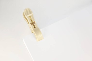 Plastic clothespin and blank paper on white background. Close up of blank paper with plastic clothespin performing the role binder clip