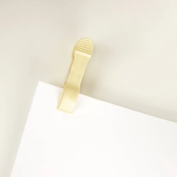 Plastic clothespin and blank paper on white background. Close up of blank paper with plastic clothespin performing the role binder clip — Stok fotoğraf