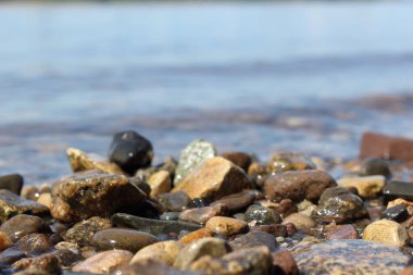 Kıyıdaki çakıl taşları bulanık arkaplanda yakınlaşıyor. Doğal arkaplan.