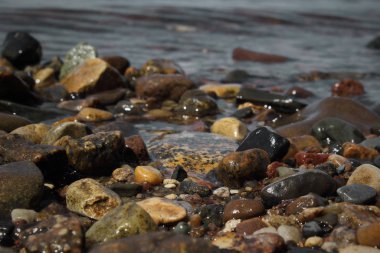 Kıyıdaki çakıl taşları bulanık arkaplanda yakınlaşıyor. Doğal arkaplan.