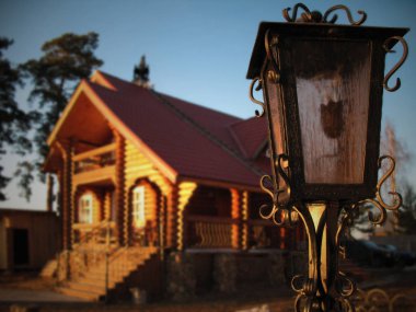 Street lamp close-up on the background of a wooden house. Blurred wooden house with beautiful view surrounded by trees