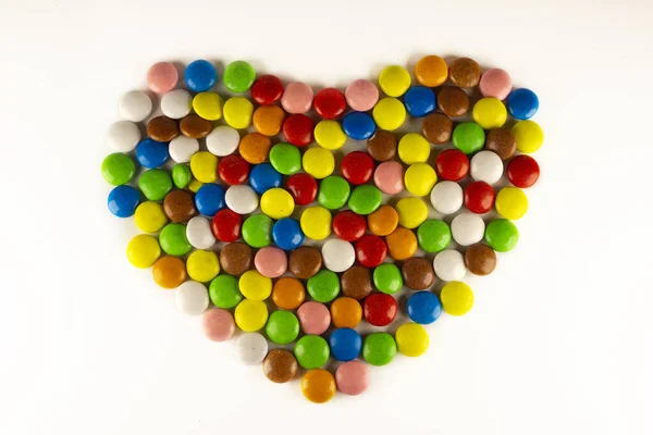 Coloridos frijoles dragee en forma de corazón sobre un fondo blanco. Fondo decorativo. Primer plano. —  Fotos de Stock