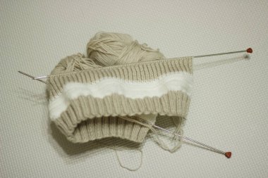 Brown knitting on light background .Knitting needles and skeins of wool, hand knitting. Selective focus