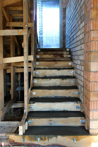 正在施工的混凝土楼梯的金属加固和木制模板。建造新大楼的阶梯。楼梯还没修完呢在房子里建造楼梯的过程. — 图库照片