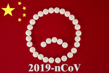 Beyaz tabletlerden yapılmış gülen surat ve kırmızı arka planda 2019 ncov yazılı haplar. 2019 Roman Coronavirus 2019-ncov konsepti.