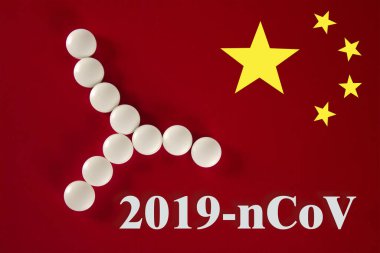 Beyaz tabletlerden yapılmış bir bakteri hücresi. Üzerinde 2019 yazılıydı. Çin bayrağının kırmızı arka planında, üst görünümde. 2019 Roman Coronavirus 2019-ncov konsepti.