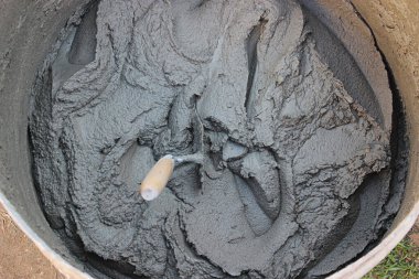 İnşaat alanındaki malzemelerle birlikte çimento karışımı. Metal kovaya alçı döşeme aleti. Seçici odak