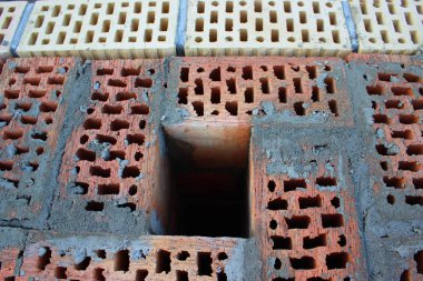 Betonla dolu kırmızı tuğladan bir duvardaki egzoz borusu. Sarı ve kahverengi tuğlalarla çevrili. Seçici odaklanma. Yapı konsepti. İnşaatın sembolü olarak tamamlanmamış ev.