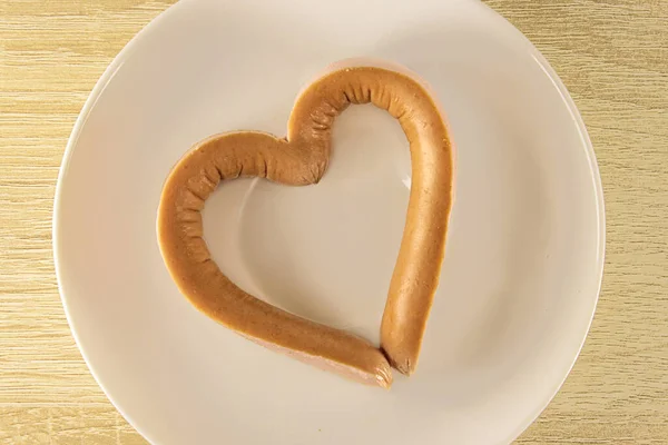 Romantyczne śniadanie w Walentynki: kiełbasa w kształcie serca, przekłuta wykałaczką na talerzu. Jak zrobić pyszne i kreatywne kiełbasy.Fast food Walentynki. — Zdjęcie stockowe