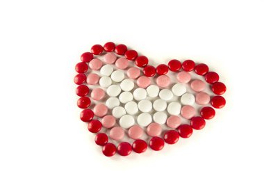 Colorful dragee beans in the shape of a heart on a white background. Decoration background. Closeup