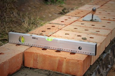 Duvardaki Kırmızı Tuğlalar. Seçici odaklanma. Duvarın üstünde kırmızı tuğlalar, spatula, kırmızı tuğla, inşaat konsepti. Bitmemiş bir evin bodrumunda duran tuğlalar ve mallar.