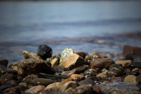 Каменные камни на берегу закрываются на размытом расстоянии. Естественный фон. Селективный фокус — стоковое фото