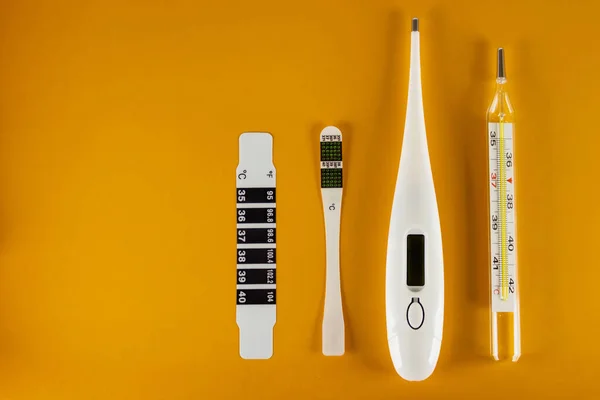 Sarı arka planda dört tip termometre vardır. Sıvı kristal, klinik, elektrik ve cıva. Sağlık ve ilaç kavramı. Boşluğu kopyala