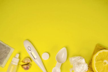 Limon, termometre, sarımsak, tıbbi çay, çerçevenin altından sarı bir zemin üzerinde kullanılmış peçete ve beyaz tıbbi tabletler. Eczane teması, tedavi ve virüsün önlenmesi. Kavram. Sonbahar, bahar, salgın.