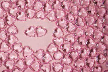 Sevgililer Günü Konsepti. Çevredeki iki kırmızı kalp. Pembe arka planda şeffaf kalpler. Cam kalp parlıyor. Bir sürü kırmızı cam kalp. Sevgililer Günü için aşk. Boşluğu kopyala.