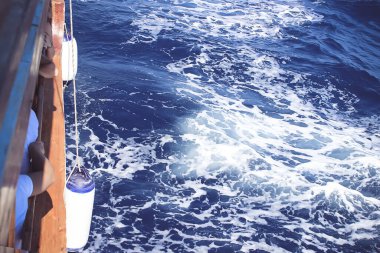 Arka planda deniz köpüğü olan Mavi Deniz Suyu 'ndaki yatın kenarı. Spreyli derin mavi deniz suyu. Okyanus suyu arkaplanı