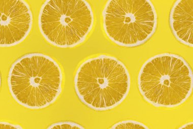 Sarı arka planda taze dilimlenmiş limon deseni. Limon meyvesi. Sarı arka planda sulu bir dilim limon